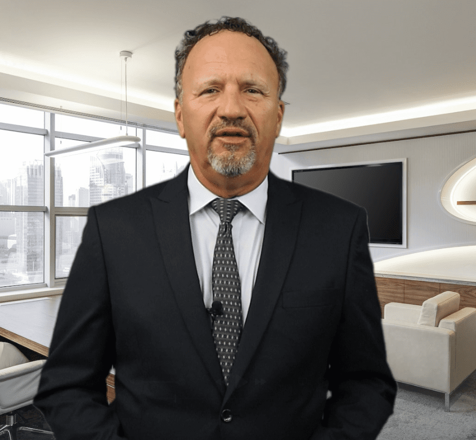 A man in a suit speaking in a modern office setting.